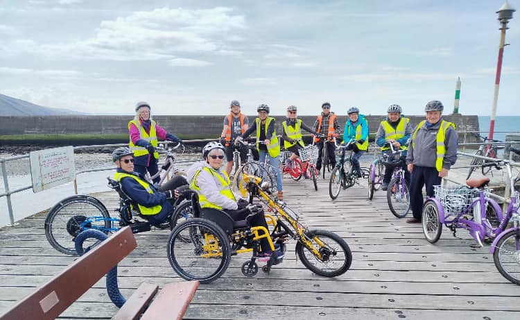 Inclusive cycling group smiling and preparing for a ride.